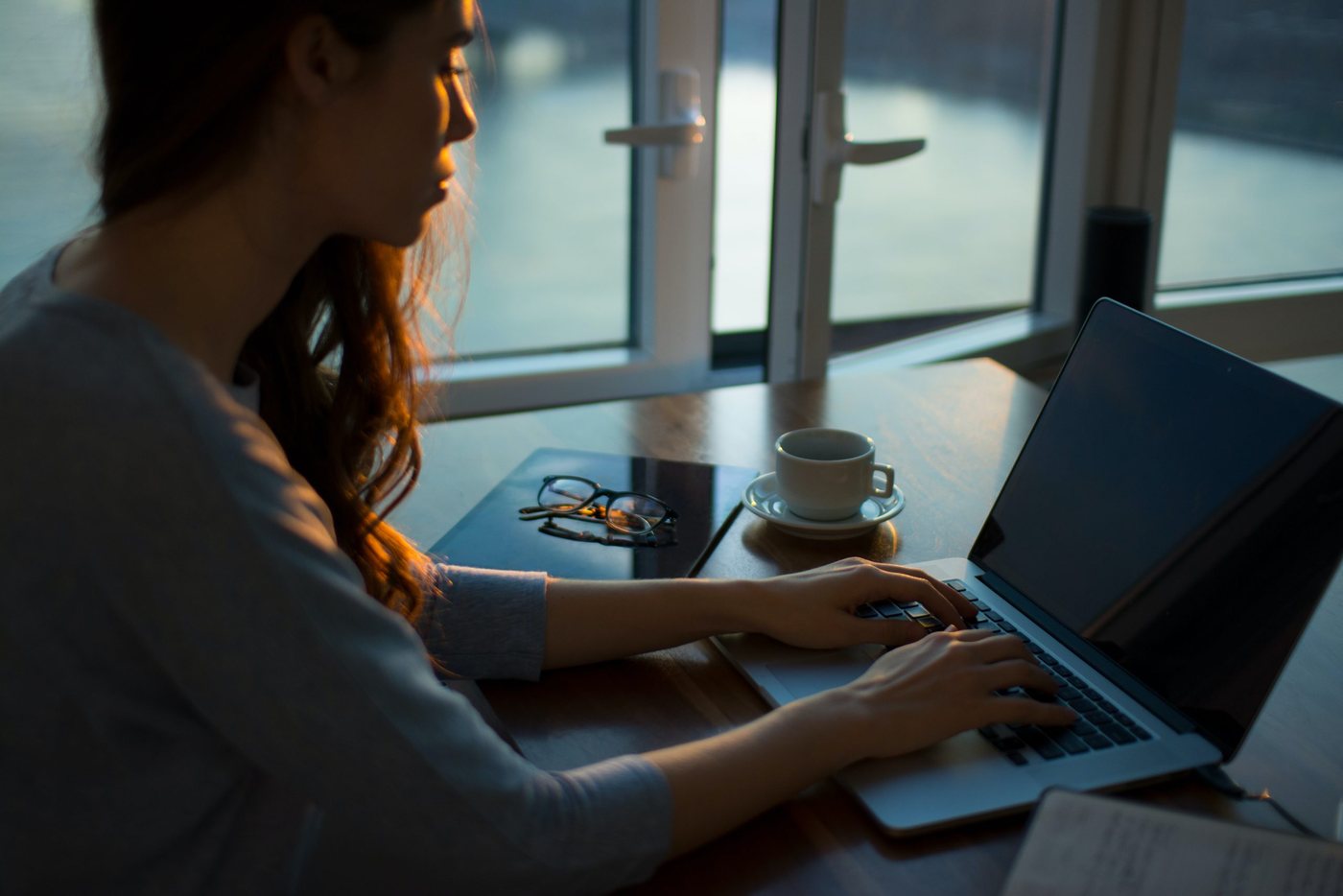 A desk with a laptop by a window